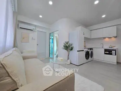 Modern open-plan living room with kitchen, featuring sleek appliances and cozy seating area.