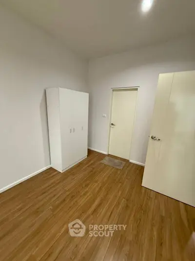 Minimalist bedroom with wooden flooring and white wardrobe