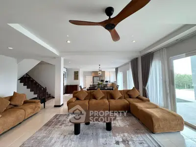 Spacious modern living room with elegant brown sofas and ceiling fan, open layout to dining area.