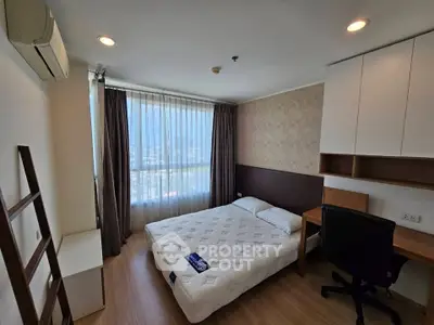 Modern bedroom with city view, featuring a cozy bed, desk, and ample storage in a high-rise apartment.