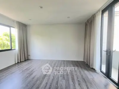 Spacious empty room with large windows and wood flooring, perfect for customization.