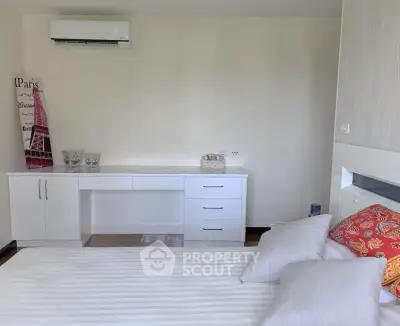 Modern bedroom with sleek white furniture and air conditioning, perfect for comfort and style.