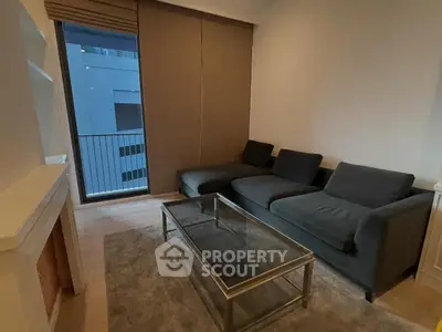 Modern living room with sleek black sofa and glass coffee table, featuring a cozy ambiance and city view.