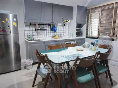 Modern kitchen with dining area, featuring sleek cabinets and stylish dining set.