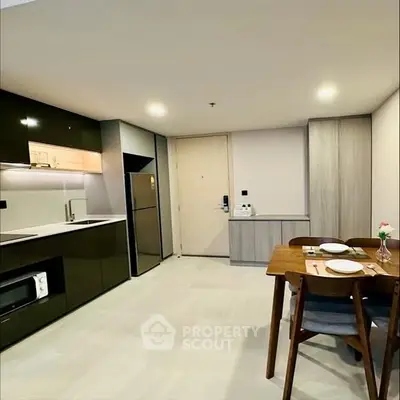 Modern kitchen with sleek cabinets and dining area in open layout apartment.