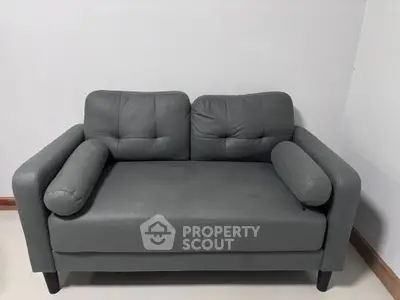 Modern gray sofa with plush cushions in a minimalist setting.