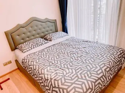 Elegant bedroom with stylish bed and natural light from large window.