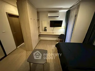 Modern bedroom with sleek furniture and wall-mounted TV in a cozy apartment.