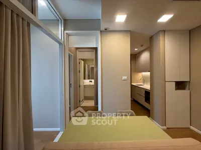 Modern apartment interior with open kitchen and dining area, featuring sleek cabinetry and neutral tones.