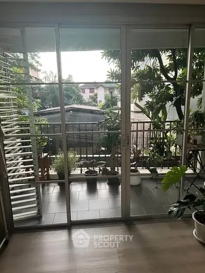 Charming balcony view with lush greenery and sliding glass doors.