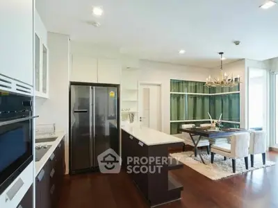 Modern open-layout kitchen with dining area, featuring sleek appliances and elegant lighting.