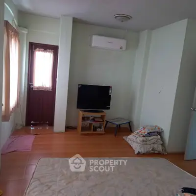 Cozy living room with TV, air conditioning, and natural light through window.