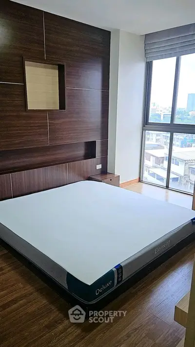 Modern bedroom with large window and stylish wooden paneling in urban apartment.
