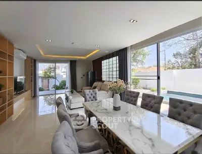 Luxurious open-plan living room with elegant dining area and pool view, featuring modern decor and ample natural light.