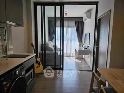 Modern apartment with open kitchen and cozy living room featuring sliding glass doors.