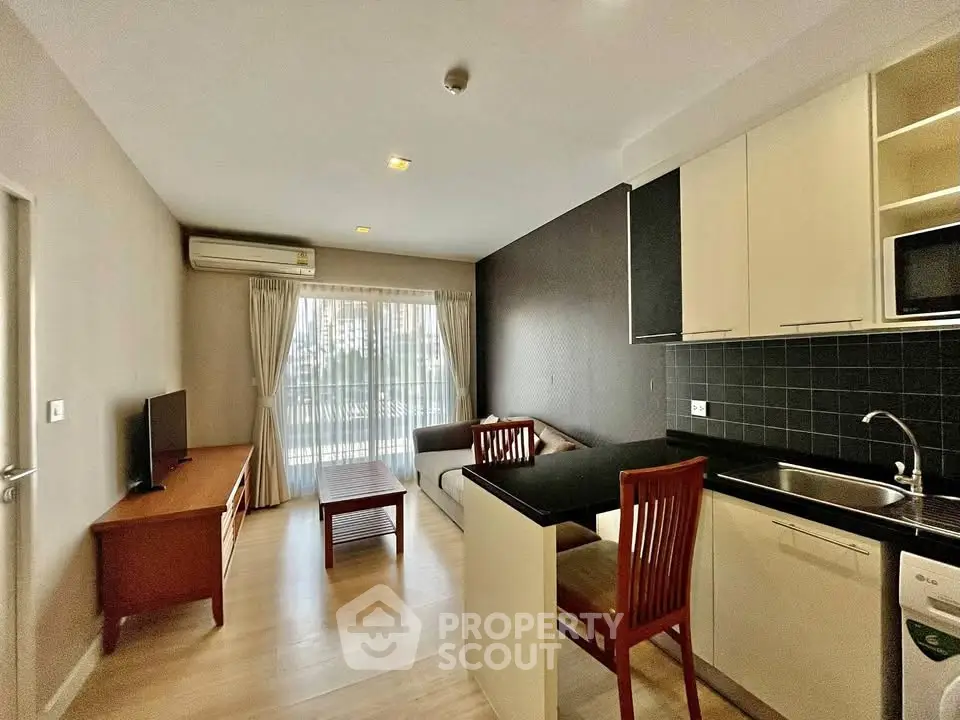 Modern open-layout living room with kitchen, featuring sleek furniture and large windows for natural light.