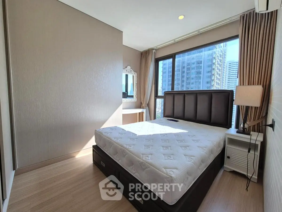 Modern bedroom with large window and city view, featuring a stylish bed and elegant decor.