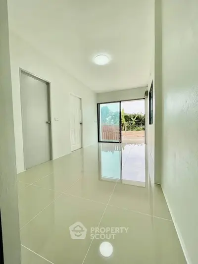 Spacious minimalist room with glossy tiled floor and large window view.