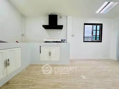 Spacious kitchen with modern hood and ample storage in a bright, airy setting.