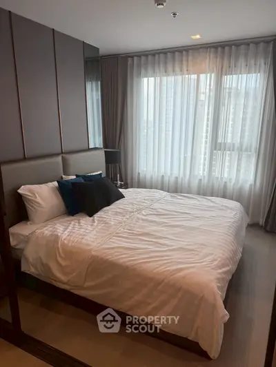 Modern bedroom with large window and stylish decor in a high-rise apartment.