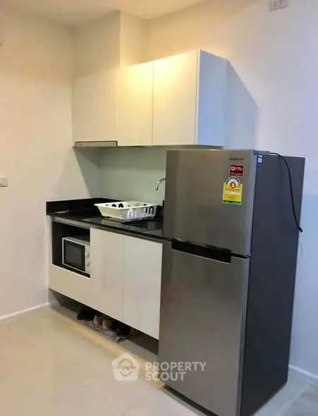 Modern kitchen with sleek cabinets and stainless steel fridge in compact layout.