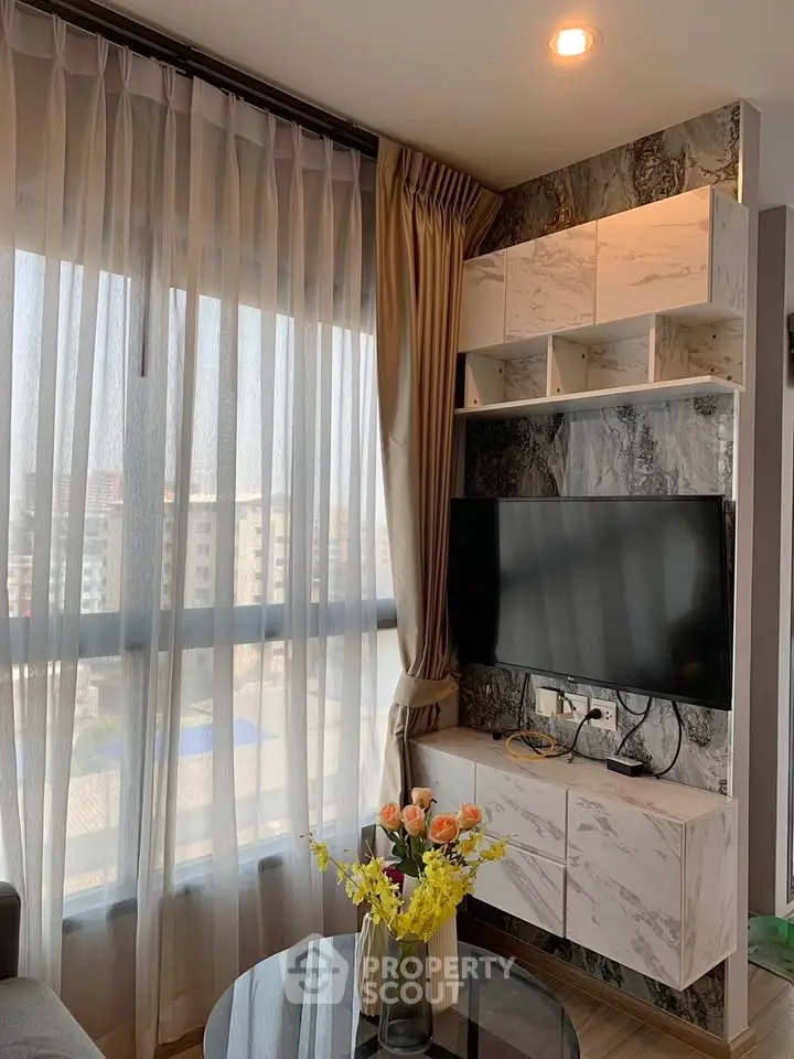 Modern living room with large window, stylish TV unit, and elegant decor in a high-rise apartment.