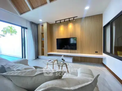 Modern living room with stylish wood paneling and large TV, featuring cozy seating and natural light.
