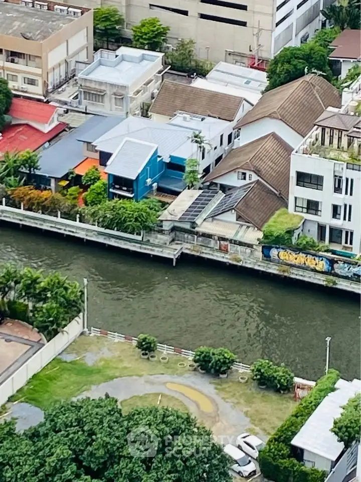 Aerial view of riverside residential area with modern houses and lush greenery.