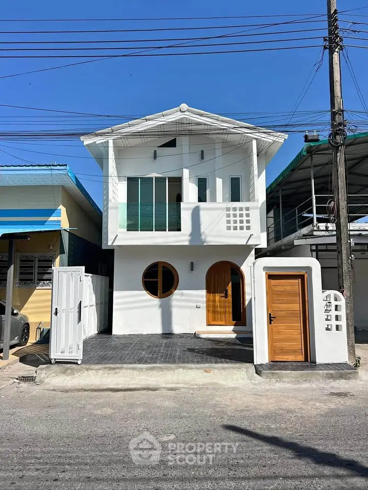 Modern two-story house with unique circular windows and wooden doors, showcasing contemporary architecture.