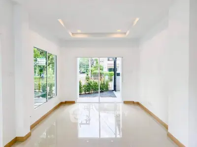 Spacious and bright living room with large windows and garden view.