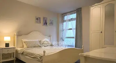 Charming bedroom with elegant white furniture and large window offering natural light.