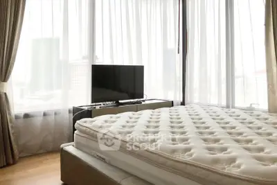 Spacious bedroom with large windows and city view, featuring a comfortable bed and modern TV setup.