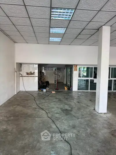 Spacious commercial space with concrete flooring and modern ceiling tiles, ideal for business setup.