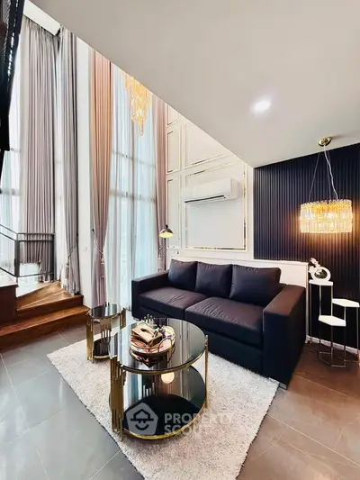 Luxurious modern living room with high ceilings, elegant chandelier, and stylish furniture.