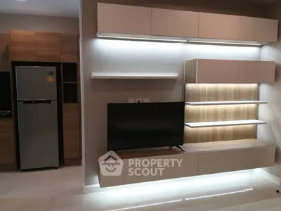 Modern living room with sleek TV unit and integrated lighting, adjacent to a stylish kitchen area.