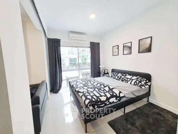 Modern bedroom with stylish decor and large window offering natural light.