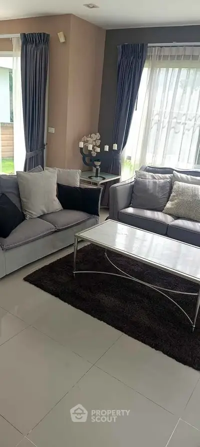 Elegant living room with modern gray sofas, large windows, and stylish decor in a bright, inviting space.