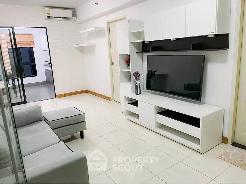 Modern living room with sleek white furniture and large TV, perfect for relaxation.
