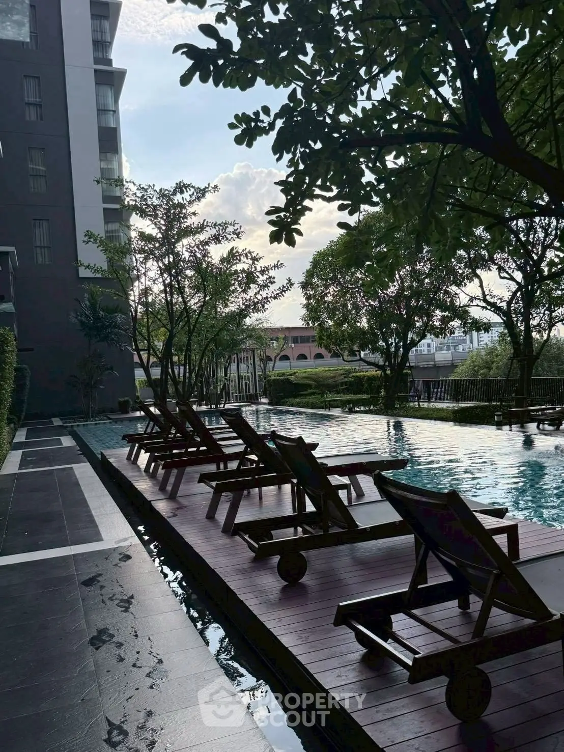 Luxurious residential pool area with stylish sun loungers and lush greenery