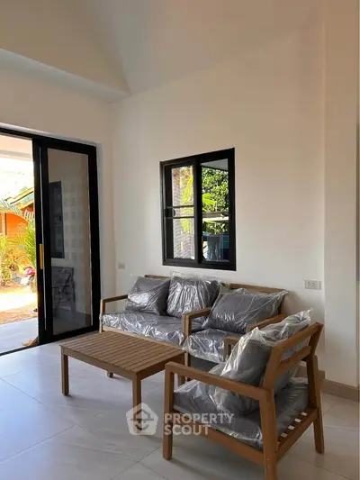 Modern living room with stylish wooden furniture and large sliding glass doors opening to a garden view.
