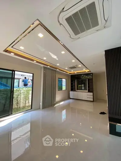 Spacious modern living room with sleek ceiling design and large windows for natural light.