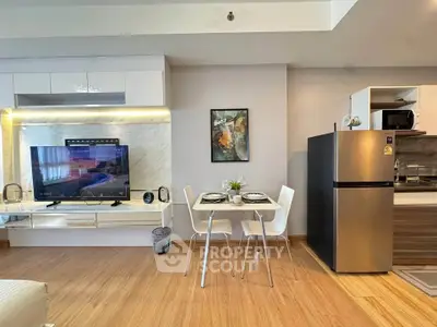 Modern open-plan living room with sleek kitchen and dining area, featuring stylish decor and appliances.