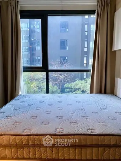 Spacious bedroom with large window offering urban view, perfect for city living.