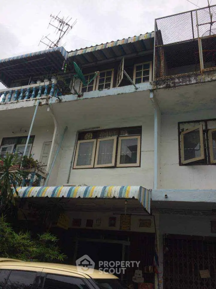 Charming multi-story townhouse with unique architectural details and colorful awnings in a vibrant neighborhood.