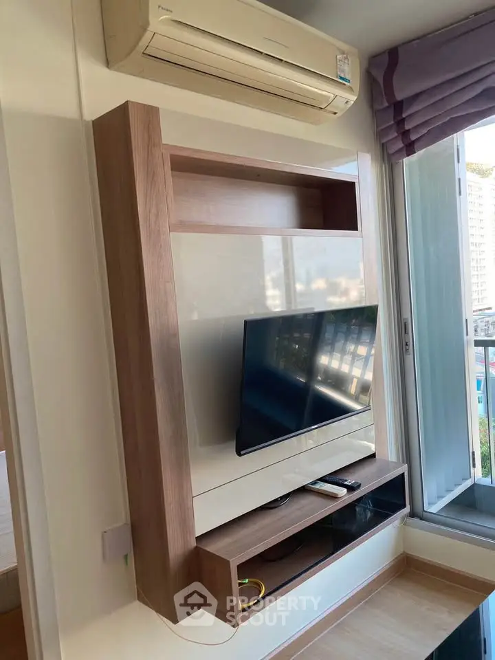 Modern living room with wall-mounted TV and air conditioning, featuring a sleek design and natural light.
