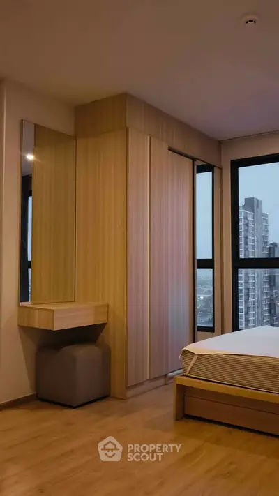 Modern bedroom with wooden flooring and large windows offering city views