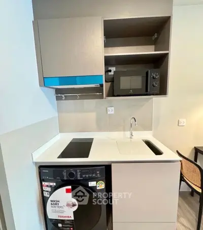 Compact modern kitchen with washing machine and microwave in stylish apartment