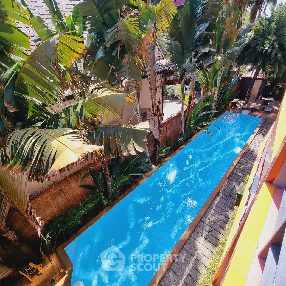 Luxurious tropical pool surrounded by lush greenery in a modern real estate property.