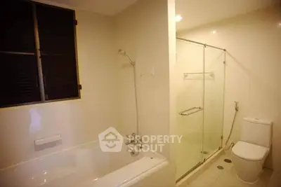 Spacious bathroom with bathtub and glass-enclosed shower in modern apartment.