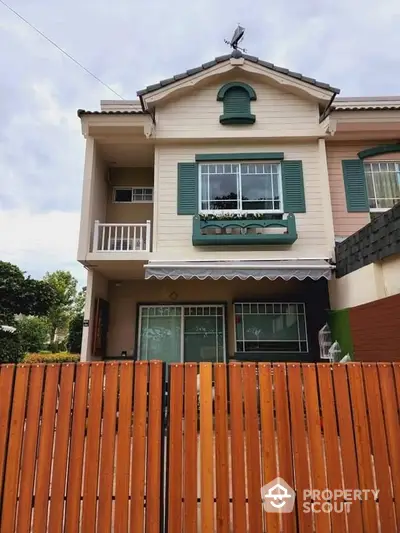 Charming two-story house with green shutters and wooden fence in a serene neighborhood.